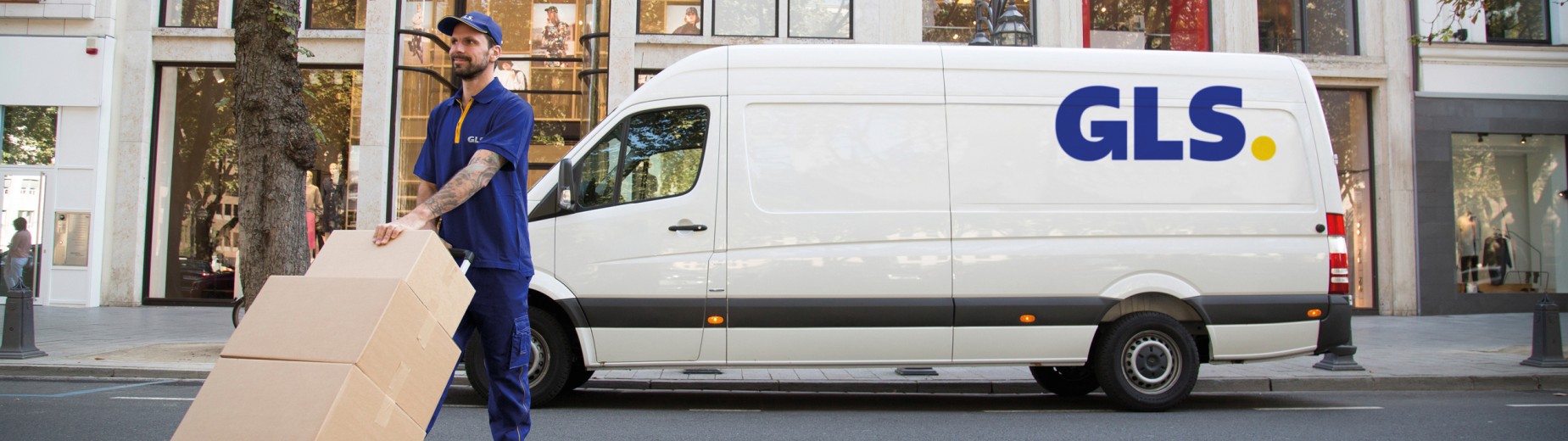 Livreur GLS manipulant des colis devant un fourgon GLS en centre-ville, illustrant le réseau de livraison national de GLS France.